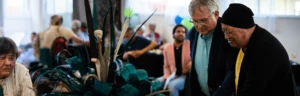 Wide angled shot of Māori man with black beanie and White man with glasses and grey hair observing something together