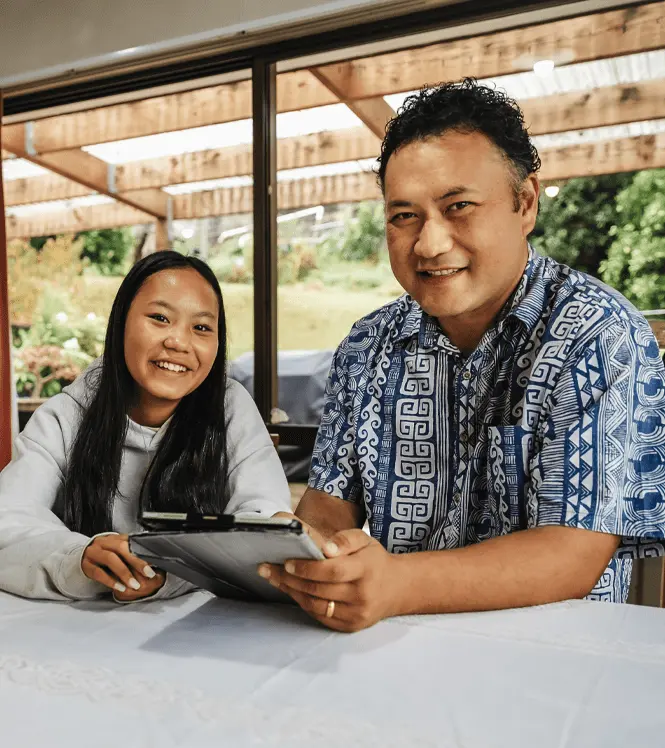 Maori Dad and daughter smiling at the camera while sitting at a table