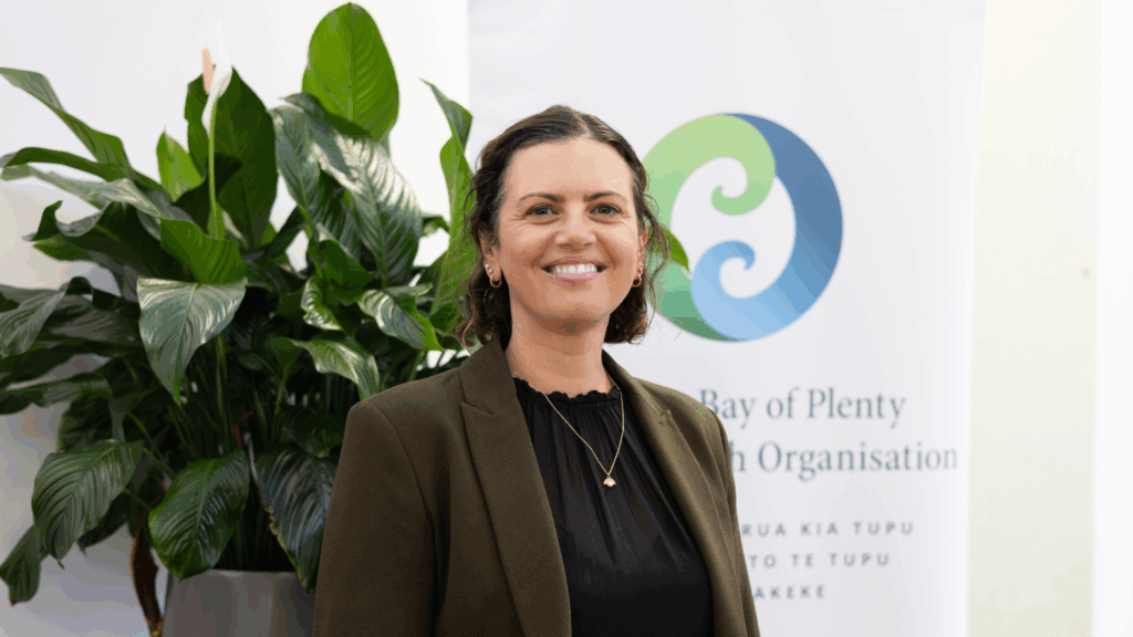 Sarah Stevenson, newly appointed interim CEO of WBOP PHO, standing in front of the Western Bay of Plenty Primary Health Organisation banner.